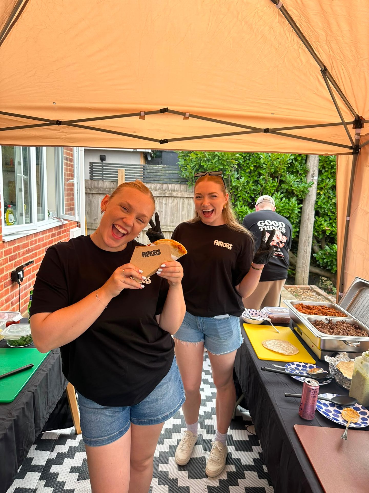 Two of the team laughing while holding a Parcels box at the stall
